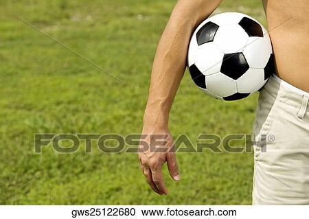 Mid section view of a man holding a soccer ball View Large Photo Image Stock Image - Mid section view of a man holding a soccer ball. Fotosearch
