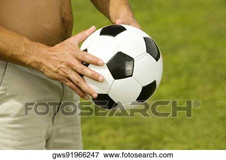 Mid section view of a man holding a soccer ball View Large Photo Image Stock Photo - Mid section view of a man holding a soccer ball. Fotosearch