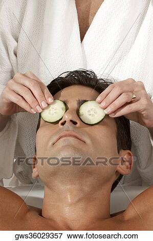 Mid section view of a massage therapist putting slices of cucumber on a young man's eyes View Large Photo Image Stock Photo - Mid section view of a massage therapist putting slices of cucumber on a young man's eyes. Fotosearch