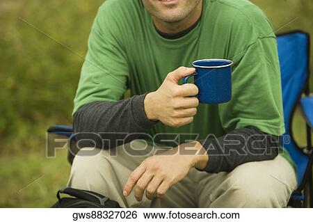 Mid section view of a mid adult man holding a coffee cup View Large Photo Image Stock Photograph - Mid section view of a mid adult man holding a coffee cup. Fotosearch
