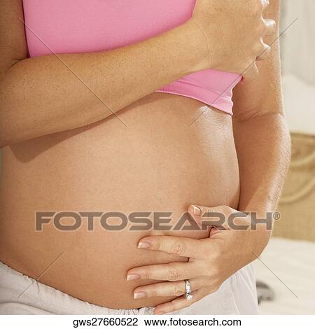 Mid section view of a pregnant woman touching her abdomen View Large Photo Image Stock Image - Mid section view of a pregnant woman touching her abdomen. Fotosearch
