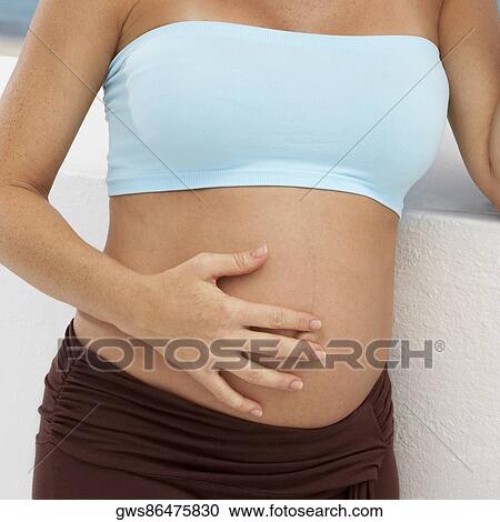 Mid section view of a pregnant woman touching her abdomen View Large Photo Image Stock Image - Mid section view of a pregnant woman touching her abdomen. Fotosearch