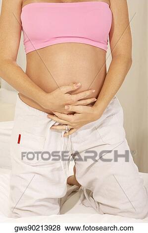 Mid section view of a pregnant woman touching her abdomen View Large Photo Image Stock Photo - Mid section view of a pregnant woman touching her abdomen. Fotosearch