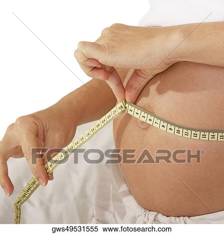 Mid section view of a pregnant woman measuring her abdomen with a measuring tape View Large Photo Image Stock Photography - Mid section view of a pregnant woman measuring her abdomen with a measuring tape. Fotosearch
