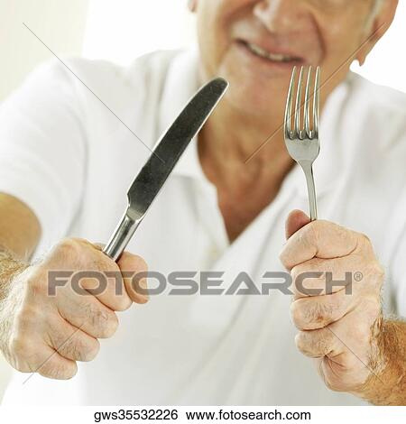 Mid section view of a senior man holding a table knife and a fork View Large Photo Image Stock Photograph - Mid section view of a senior man holding a table knife and a fork. Fotosearch