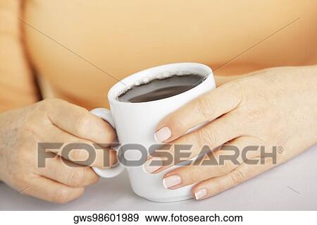 Stock Photo - Mid section view of a senior woman holding a cup of black coffee. Fotosearch