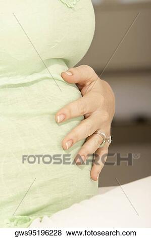 Mid section view of a woman touching her abdomen View Large Photo Image Stock Photo - Mid section view of a woman touching her abdomen. Fotosearch