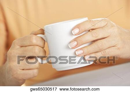 Mid section view of a woman's hand holding a cup of coffee View Large Photo Image Stock Photo - Mid section view of a woman's hand holding a cup of coffee. Fotosearch