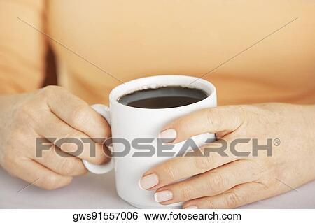 Mid section view of a woman's hand holding a cup of coffee View Large Photo Image Stock Photograph - Mid section view of a woman's hand holding a cup of coffee. Fotosearch