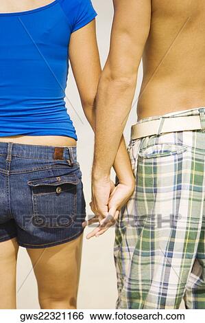 Mid section view of a young couple holding hands View Large Photo Image Stock Photograph - Mid section view of a young couple holding hands. Fotosearch
