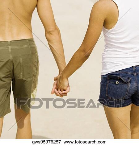 Mid section view of a young man and a teenage girl holding hands on the beach View Large Photo Image Stock Photo - Mid section view of a young man and a teenage girl holding hands on the beach. Fotosearch