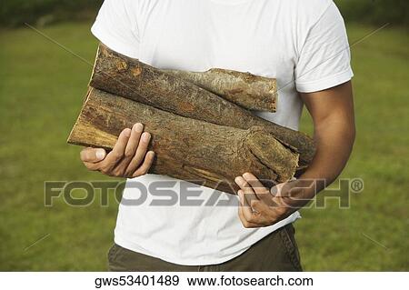Mid section view of a young man holding firewood View Large Photo Image Stock Photo - Mid section view of a young man holding firewood. Fotosearch