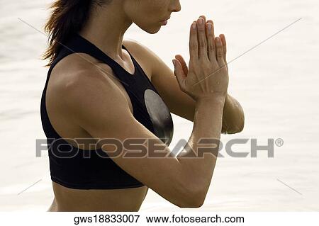 Mid section view of a young woman meditating View Large Photo Image Stock Photo - Mid section view of a young woman meditating. Fotosearch