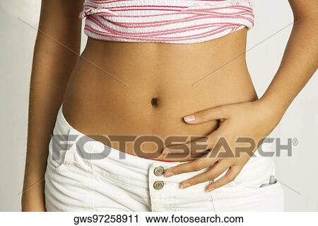 Stock Image - Mid section view of a young woman with her hands on her stomach. Fotosearch