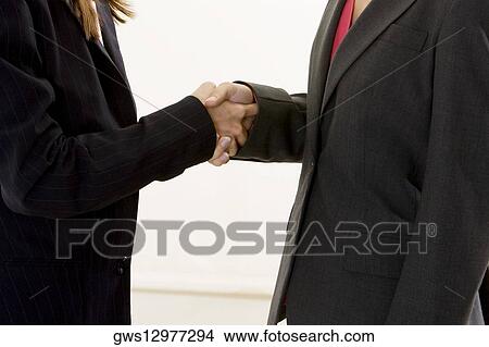 Picture - Mid section view of two businesswomen shaking hands. Fotosearch