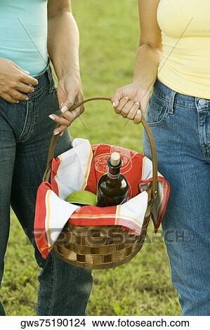 Picture - Mid section view of two women holding a picnic basket. Fotosearch