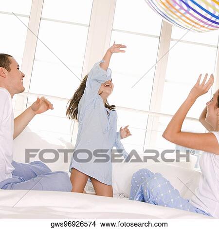 Picture - Parents playing with their daughter on the bed. Fotosearch