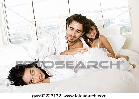 Parents with their daughter on the bed View Large Photo Image Stock Image - Parents with their daughter on the bed. Fotosearch