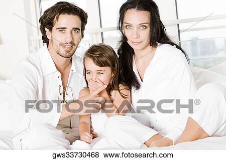 Parents with their daughter on the bed View Large Photo Image Stock Photo - Parents with their daughter on the bed. Fotosearch