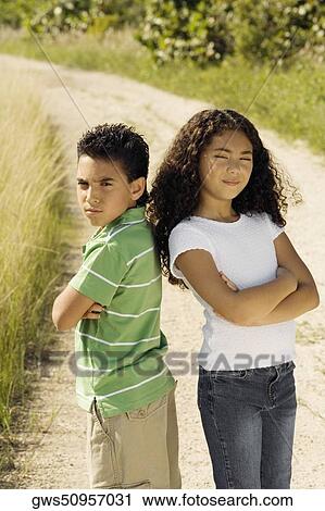 Portrait of a boy and a girl standing back to back with their arms crossed View Large Photo Image Stock Image - Portrait of a boy and a girl standing back to back with their arms crossed. Fotosearch