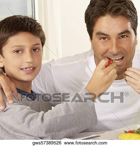Portrait of a boy feeding his father a strawberry View Large Photo Image Stock Photograph - Portrait of a boy feeding his father a strawberry. Fotosearch