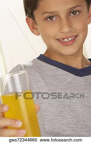 Portrait of a boy holding a glass of juice View Large Photo Image Stock Photography - Portrait of a boy holding a glass of juice. Fotosearch