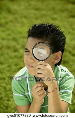 Stock Image - Portrait of a boy looking through a magnifying glass. Fotosearch
