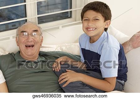 Portrait of a boy sitting with his grandfather on a couch View Large Photo Image Stock Photography - Portrait of a boy sitting with his grandfather on a couch. Fotosearch