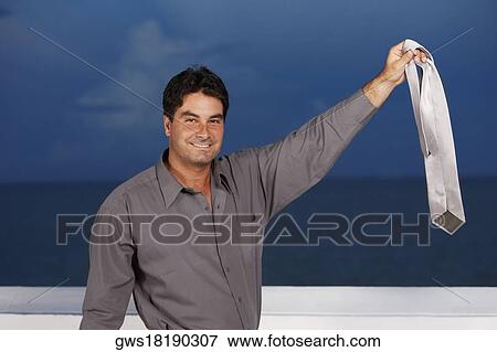 Portrait of a businessman holding a tie in his raised hand View Large Photo Image Stock Photo - Portrait of a businessman holding a tie in his raised hand. Fotosearch