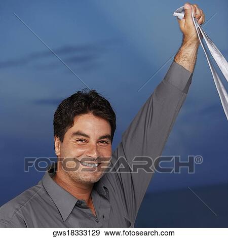 Portrait of a businessman holding a tie in his raised hand View Large Photo Image Stock Photo - Portrait of a businessman holding a tie in his raised hand. Fotosearch