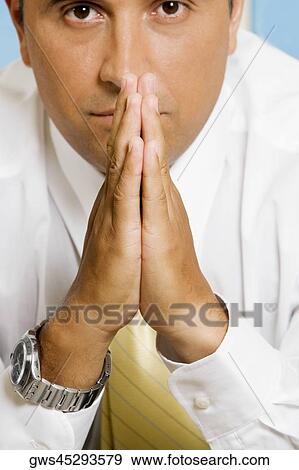 Stock Photo - Portrait of a businessman sitting in a prayer position. Fotosearch