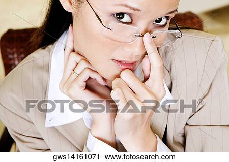Stock Image - Portrait of a businesswoman adjusting her eyeglasses. Fotosearch