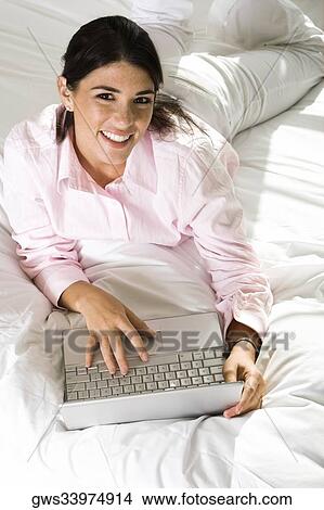 Portrait of a businesswoman lying on the bed with a laptop View Large Photo Image Picture - Portrait of a businesswoman lying on the bed with a laptop. Fotosearch