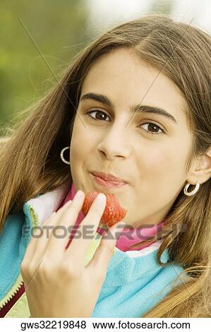 Portrait of a girl eating a strawberry View Large Photo Image Stock Photo - Portrait of a girl eating a strawberry. Fotosearch