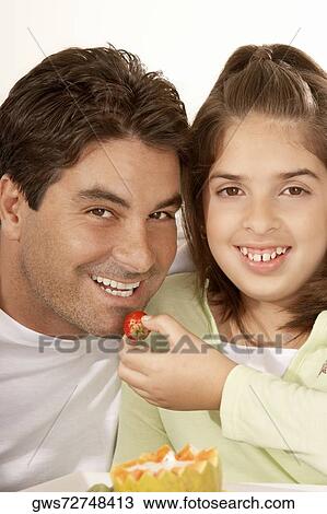 Portrait of a girl feeding her father a strawberry View Large Photo Image Stock Image - Portrait of a girl feeding her father a strawberry. Fotosearch