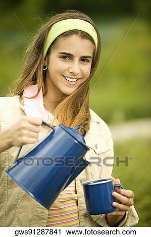 Portrait of a girl holding a mug and a kettle View Large Photo Image Stock Image - Portrait of a girl holding a mug and a kettle. Fotosearch