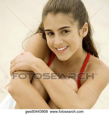 Stock Photo - Portrait of a girl sitting on the beach smiling. Fotosearch