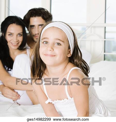 Portrait of a girl smiling with her parents behind her View Large Photo Image Stock Photo - Portrait of a girl smiling with her parents behind her. Fotosearch