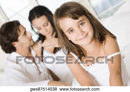 Portrait of a girl smiling with her parents behind her View Large Photo Image Stock Photo - Portrait of a girl smiling with her parents behind her. Fotosearch