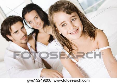 Portrait of a girl smiling with her parents behind her View Large Photo Image Stock Photograph - Portrait of a girl smiling with her parents behind her. Fotosearch