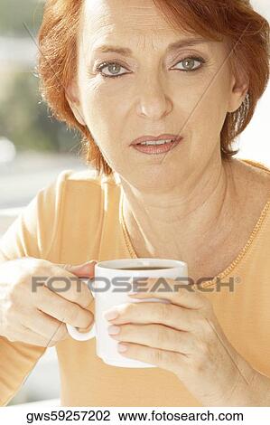 Stock Image - Portrait of a mature woman holding a cup of coffee. Fotosearch