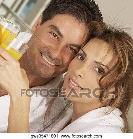 Stock Image - Portrait of a mid adult couple toasting with glasses of juice. Fotosearch