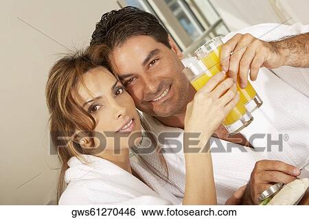 Portrait of a mid adult couple toasting with glasses of juice View Large Photo Image Stock Photograph - Portrait of a mid adult couple toasting with glasses of juice. Fotosearch