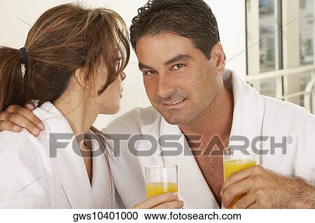 Stock Image - Portrait of a mid adult man and a mid adult woman holding a glass of juice. Fotosearch
