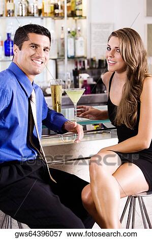 Portrait of a mid adult man and a young woman sitting in a bar View Large Photo Image Stock Photo - Portrait of a mid adult man and a young woman sitting in a bar. Fotosearch