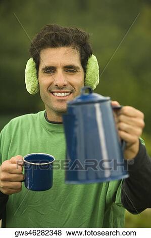 Portrait of a mid adult man holding a coffee cup and a kettle View Large Photo Image Stock Photo - Portrait of a mid adult man holding a coffee cup and a kettle. Fotosearch