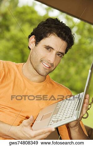 Portrait of a mid adult man holding a laptop View Large Photo Image Stock Photo - Portrait of a mid adult man holding a laptop. Fotosearch