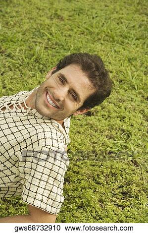 Stock Image - Portrait of a mid adult man lying on the grass. Fotosearch