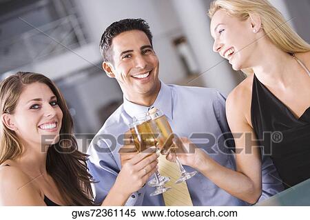 Portrait of a mid adult man raising a toast with two young women View Large Photo Image Stock Photography - Portrait of a mid adult man raising a toast with two young women. Fotosearch