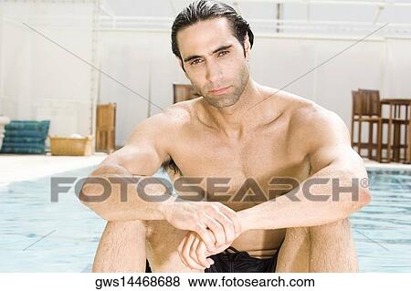 Stock Photo - Portrait of a mid adult man sitting at the poolside. Fotosearch